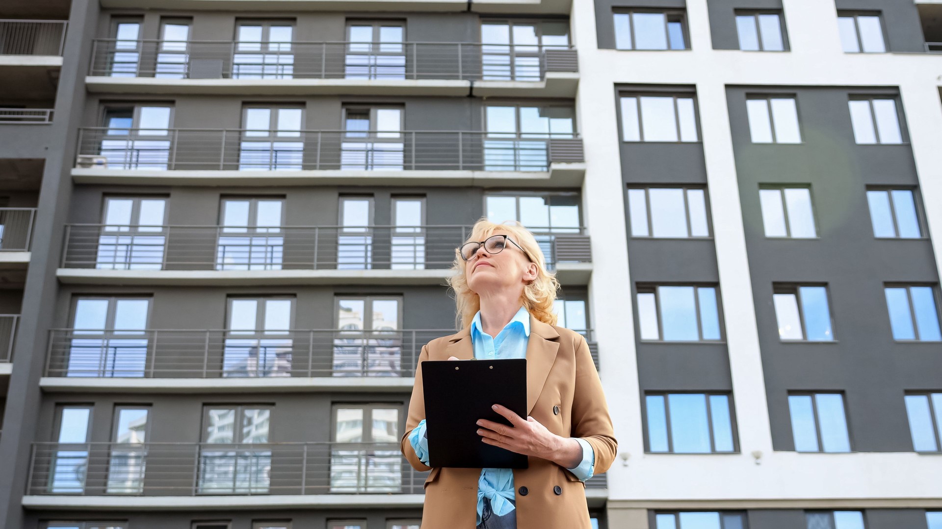 Woman entrepreneur looks around making notes on clipboard